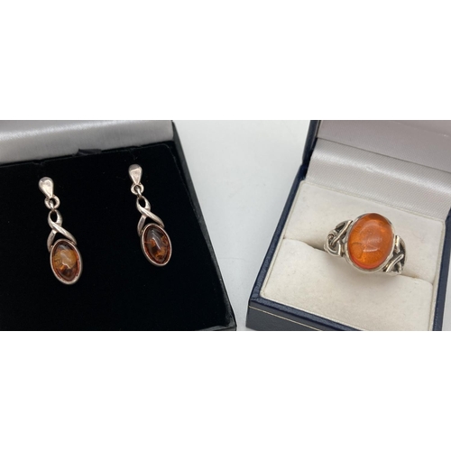 1155 - A silver and amber Celtic design dress ring and matching earrings. Ring set with oval shaped amber c... 