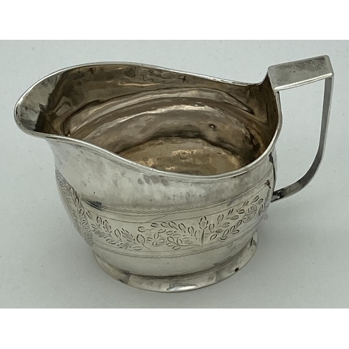 1219 - A Georgian silver cream jug with engraved floral banded design. Featuring a wreathed circular shaped... 