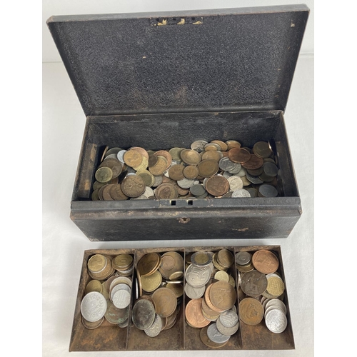 13 - A vintage black metal cash tin containing a collection of vintage British and foreign coins. To incl... 