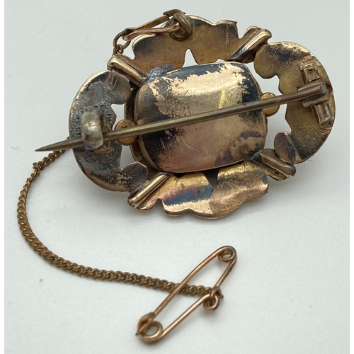 1002 - A Victorian yellow metal brooch set with carved coral stone, complete with safety chain. Tests as 8c... 