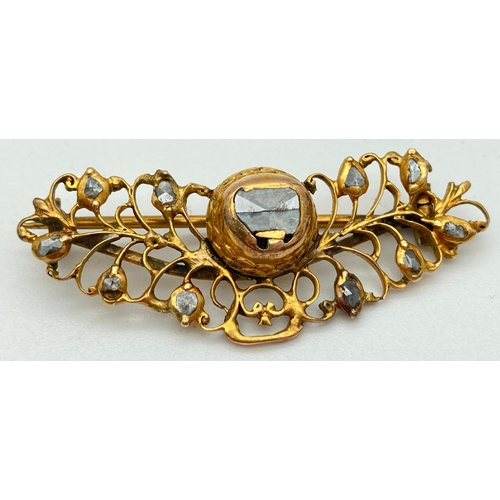 1030 - A decorative open work design yellow metal brooch set with rough cut diamonds. Pin back fixing with ... 