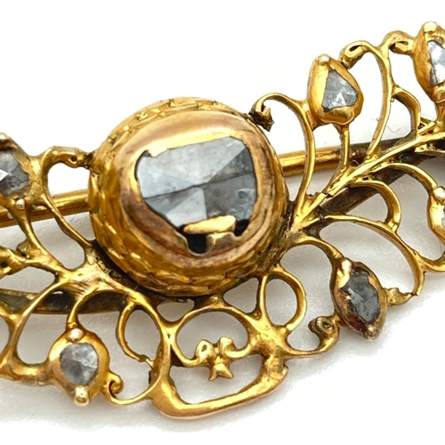 1030 - A decorative open work design yellow metal brooch set with rough cut diamonds. Pin back fixing with ... 