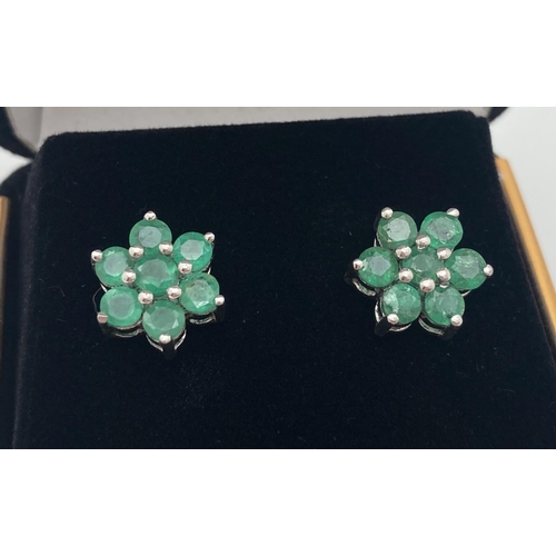 1070 - A pair of silver flower design stud style earrings each set with 7 round cut emeralds. Posts marked ... 