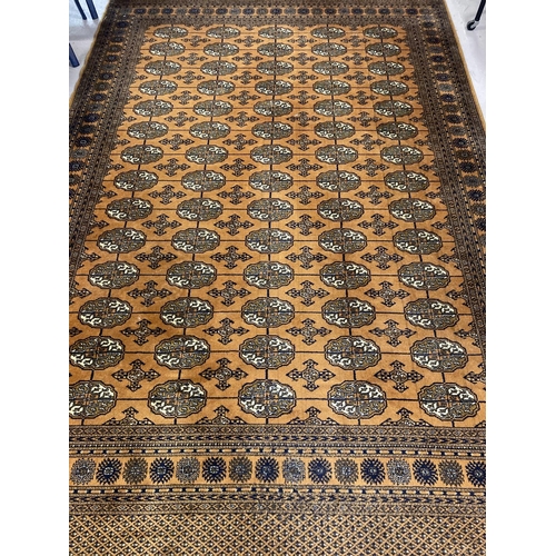 1417 - A large ochre coloured Indian style rug with brown, black and cream colours in a geometric design. T... 