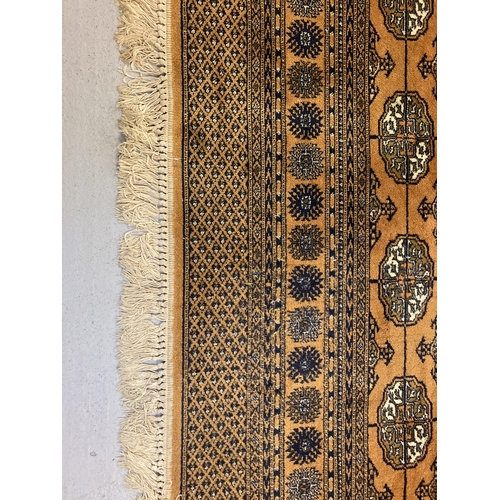 1417 - A large ochre coloured Indian style rug with brown, black and cream colours in a geometric design. T... 