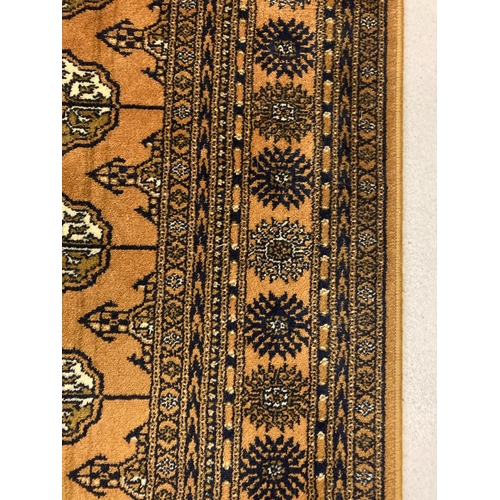 1417 - A large ochre coloured Indian style rug with brown, black and cream colours in a geometric design. T... 