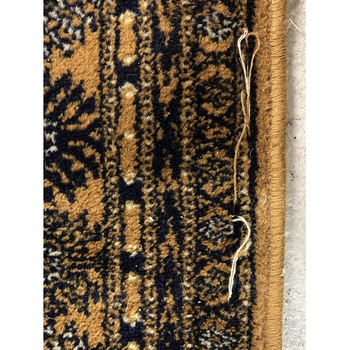 1417 - A large ochre coloured Indian style rug with brown, black and cream colours in a geometric design. T... 