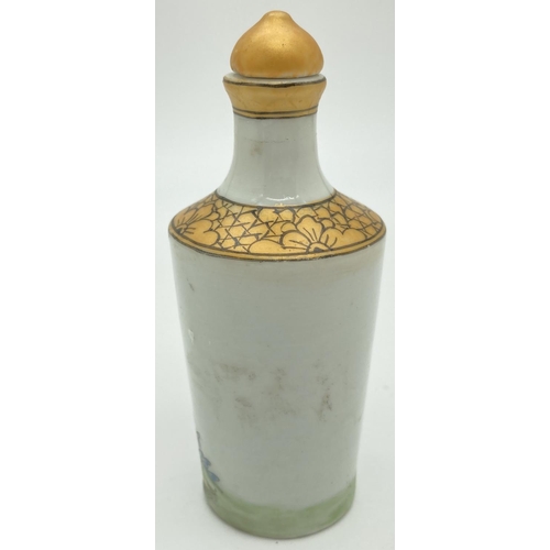 1301 - A small Chinese ceramic snuff bottle with painted erotic scene. Gilt painted stopper and top rim. Ha... 