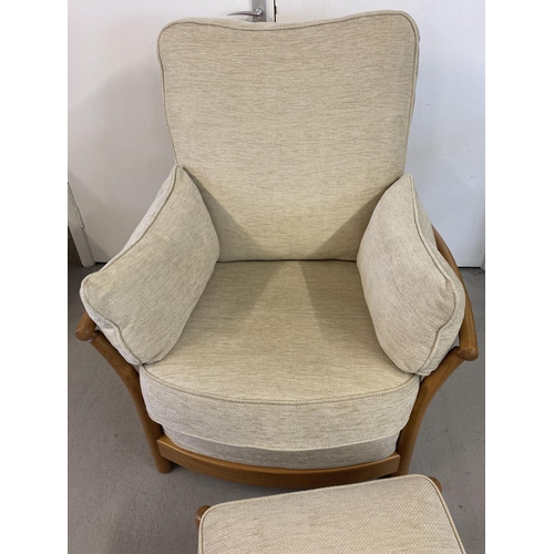 1443 - A modern Ercol light elm framed armchair and matching footstool, with cream coloured cushions. With ... 