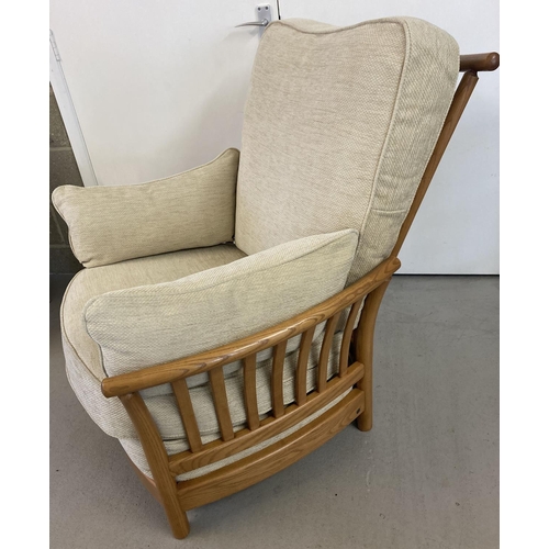 1443 - A modern Ercol light elm framed armchair and matching footstool, with cream coloured cushions. With ... 