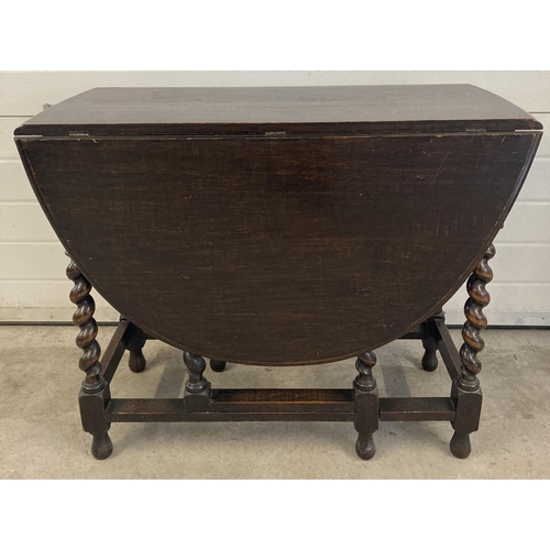 1454 - A Victorian dark oak barley twist drop leaf, gate leg dining table. With oval shaped top and bun fee... 