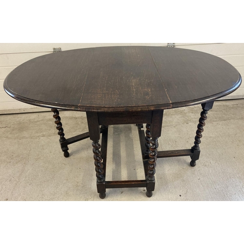 1454 - A Victorian dark oak barley twist drop leaf, gate leg dining table. With oval shaped top and bun fee... 