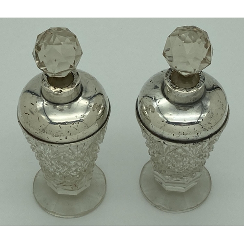 1194 - A pair of early 20th century cut glass scent bottles with silver collars and shoulders. Worn silver ... 