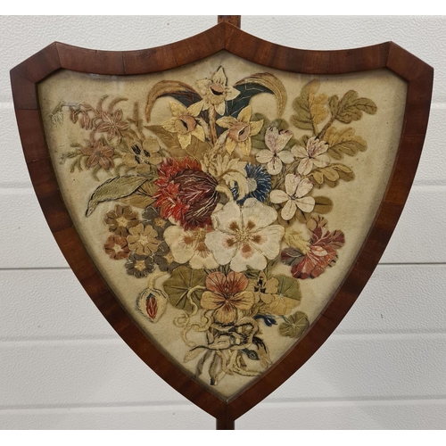 1464 - An antique Regency mahogany pole screen with embroidered felt floral panel in a shield shaped frame.... 