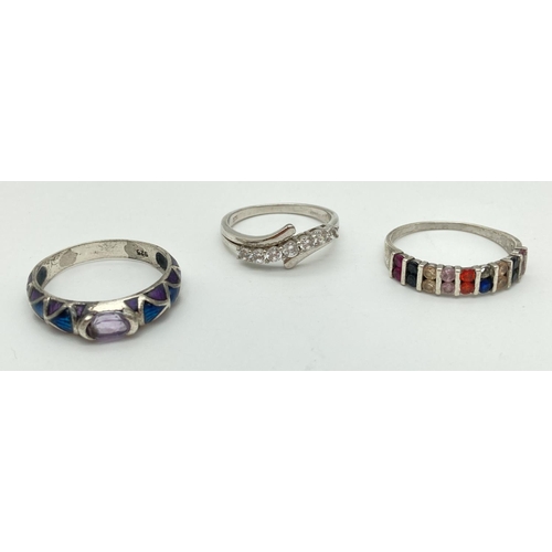 1052 - 3 large size stone set silver dress rings. A crossover band style set with clear stones, a half eter... 