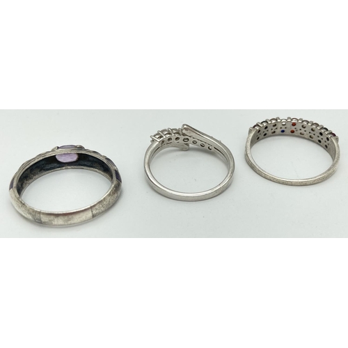 1052 - 3 large size stone set silver dress rings. A crossover band style set with clear stones, a half eter... 