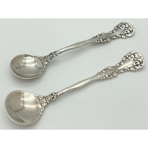 1196 - 2 vintage decorative silver salt spoons with scroll and floral detail. Both Marked Sterling to back.... 