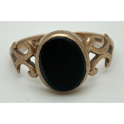 1069 - A vintage 9ct gold dress ring set with central oval onyx stone and with decorative shoulders. Fully ... 