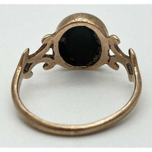 1069 - A vintage 9ct gold dress ring set with central oval onyx stone and with decorative shoulders. Fully ... 