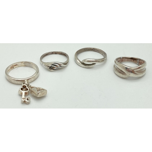 1080 - 4 silver dress rings, 3 with a twisted design and 1 with clear stone set key & bag shaped charms. In... 