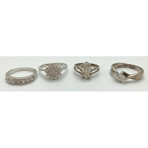 1086 - 4 silver and clear stone set rings, in varying styles and sizes. A cubic zirconia cluster ring (size... 