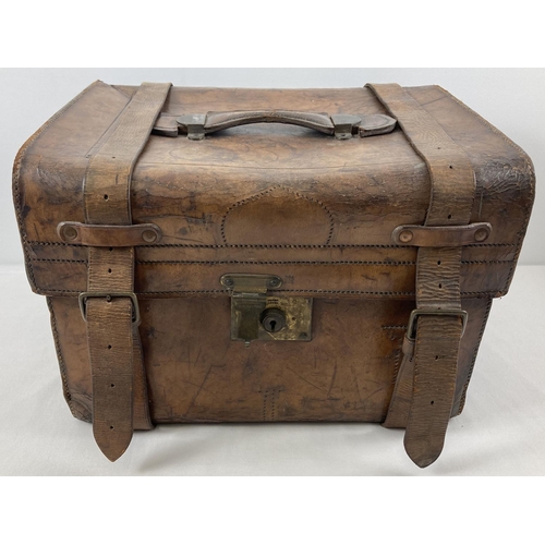 1383 - An antique leather travelling trunk with brass fixings, leather fastening straps and carry handle. B... 