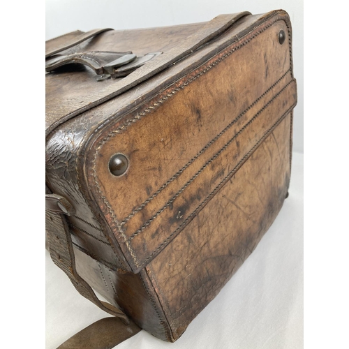 1383 - An antique leather travelling trunk with brass fixings, leather fastening straps and carry handle. B... 