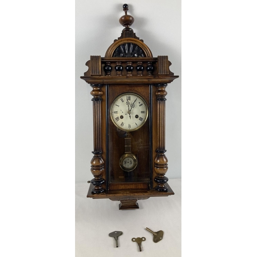 1256 - An antique wooden cased wall clock with turned finial & column detail and RA pendulum. Glass panelle... 