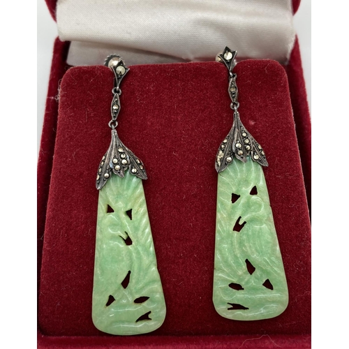 1004 - A pair of antique carved jade drop earrings with 935 silver mounts set with marcasites. Screw back f... 