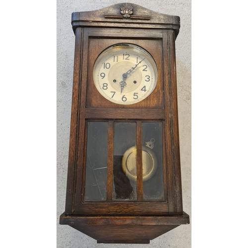 1259 - A vintage dark wood cased wall clock with glass panelled door. Complete with key & pendulum, for spa... 