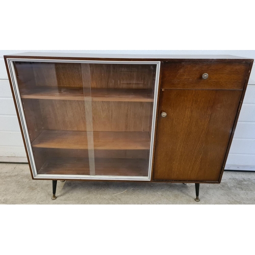 1488 - A mid century dark wood veneer display cabinet with sliding glass panel doors. Single drawer and cup... 