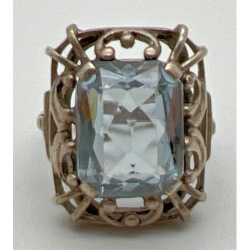 1071 - A continental silver cocktail ring set with an emerald cut pale blue spinel stone. Pierced work moun... 