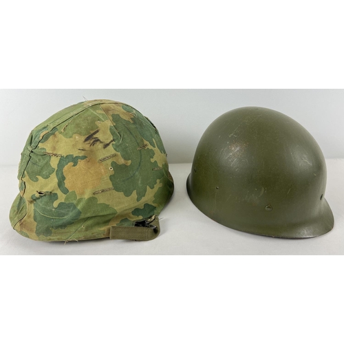 22 - A US Vietnam era M1 steel helmet with bullet damage, complete with camo cover, Firestone liner and c... 