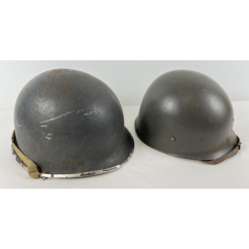 23 - A WWII US M1 steel helmet used by the US Navy, painted grey with factory cork finish. Complete with ... 