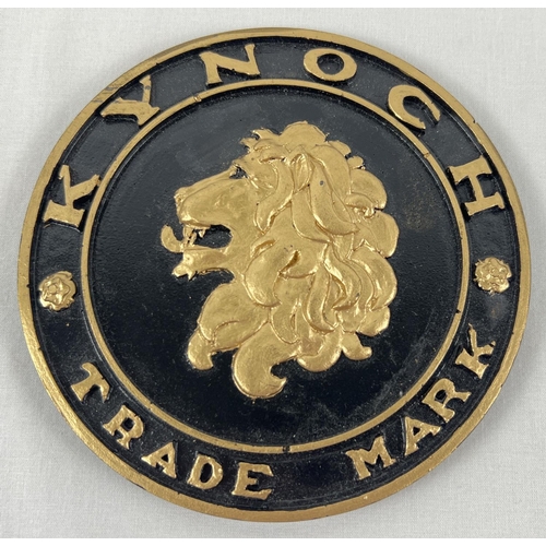 54 - A Kynoch ammunition manufacturer trade plate, painted black and gold. Approx. 13.5cm diameter.