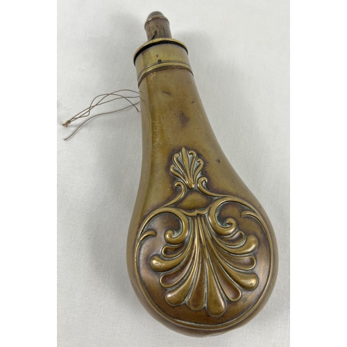 58 - An antique brass powder flask with decorative fan and scroll detail. Broken spring. Approx. 20cm lon... 
