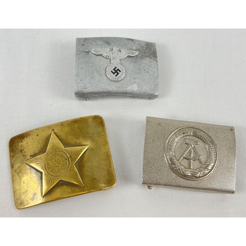 84 - 3 Military metal belt buckles. An East German silver tone buckle with hammer and compass detail, a m... 
