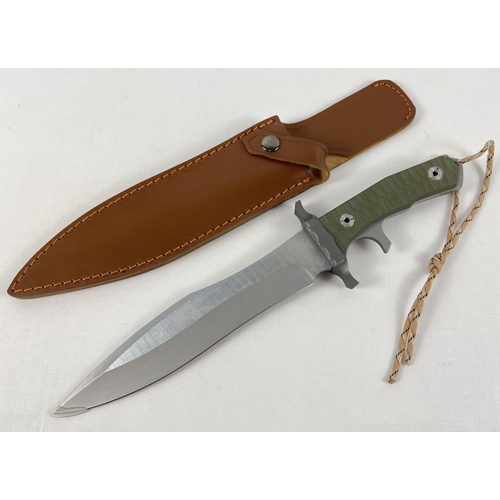 91 - A modern 9 inch blade survival knife complete with leather scabbard and wrist cord.