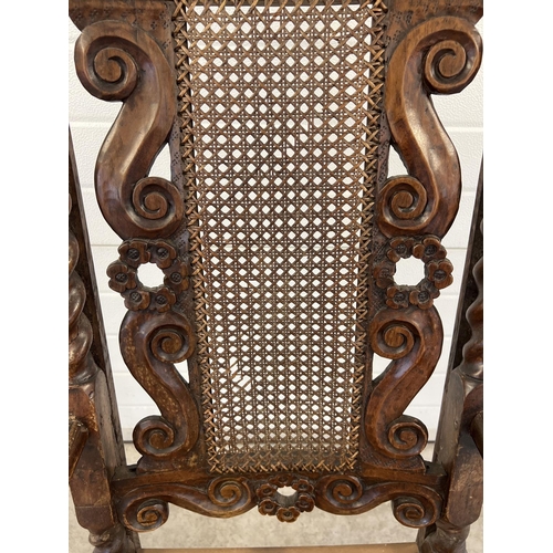 1300 - A late 17th century walnut high back armchair with barley twist columns. Carved scroll and cherub de... 