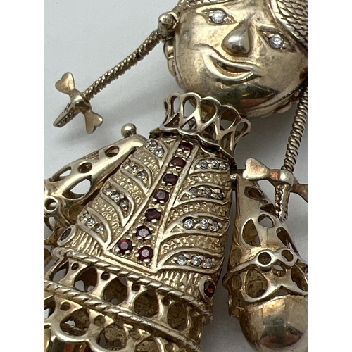 1029 - A large vintage silver gilt articulated pendant in the from of a rag doll. Set with small garnets an... 