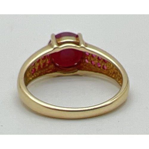 1055 - A modern design 9ct gold ruby set dress ring. Central round cut ruby with 8 small round cut rubies s... 