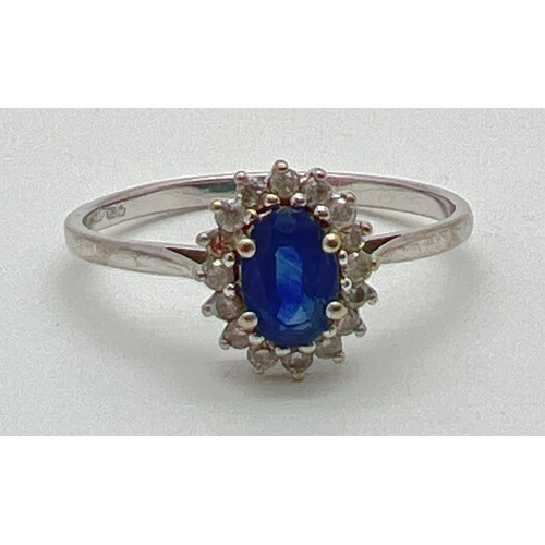 1060 - A 18ct white gold, sapphire and diamond dress ring. Central oval cut sapphire surrounded by small ro... 