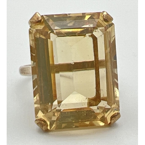 1061 - A 9ct gold cocktail ring set with a large emerald cut citrine stone. Pierced work scroll detail to m... 