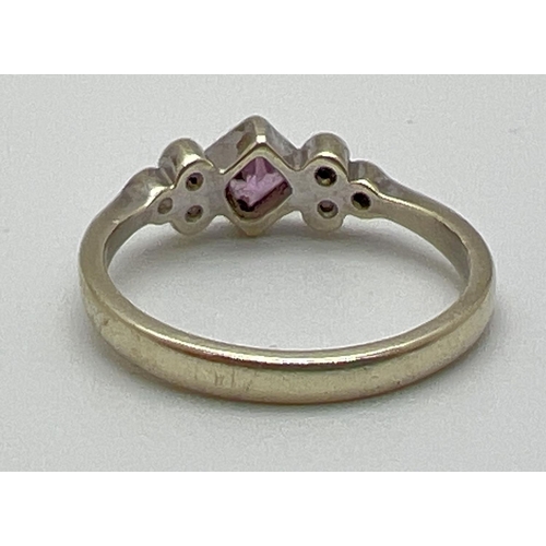 1054 - A 9ct gold pink sapphire and diamond dress ring. Central bezel set square cut pink sapphire with 3 b... 