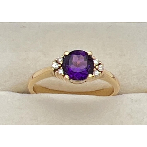 1069 - An 18ct gold amethyst and diamond dress ring. 
A central round cut .75ct amethyst with 3 small round... 