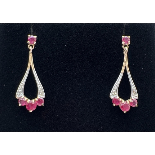 1071 - A pair of 9ct gold ruby and diamond set drop style earrings with butterfly backs. Each earring set w... 