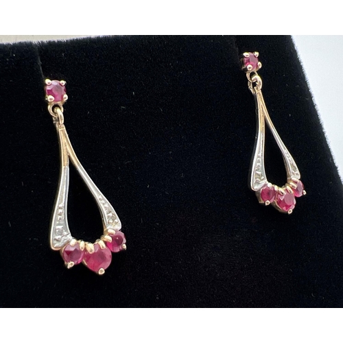 1071 - A pair of 9ct gold ruby and diamond set drop style earrings with butterfly backs. Each earring set w... 