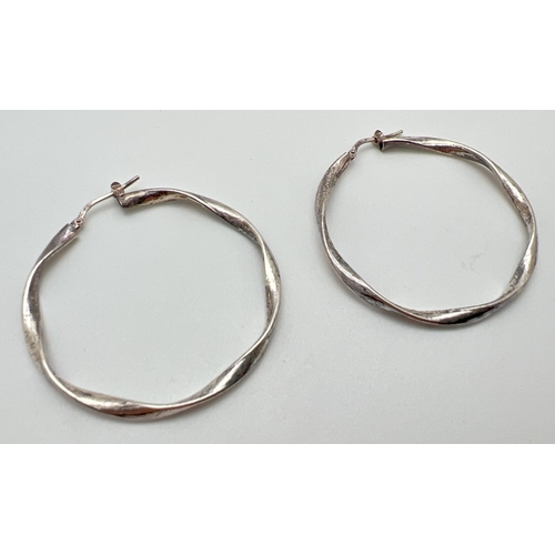 1084 - A large pair of silver twist design hoop earrings. Silver marks to posts. Approx. 4.5cm diameter.