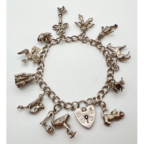 1006 - A vintage silver charm bracelet with padlock clasp and 12 charms. Charms include: a castle, bumble b... 