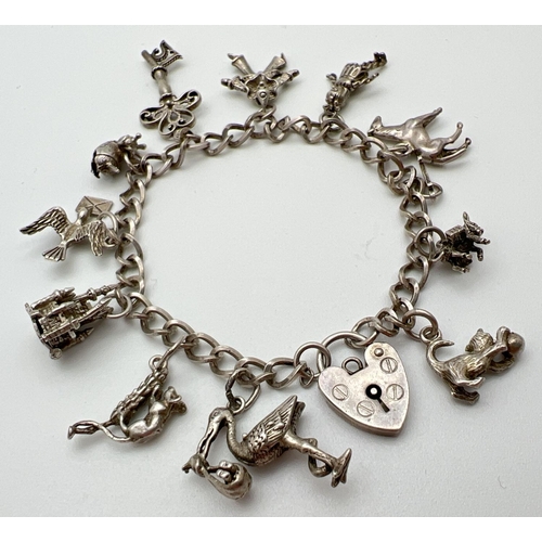 1006 - A vintage silver charm bracelet with padlock clasp and 12 charms. Charms include: a castle, bumble b... 